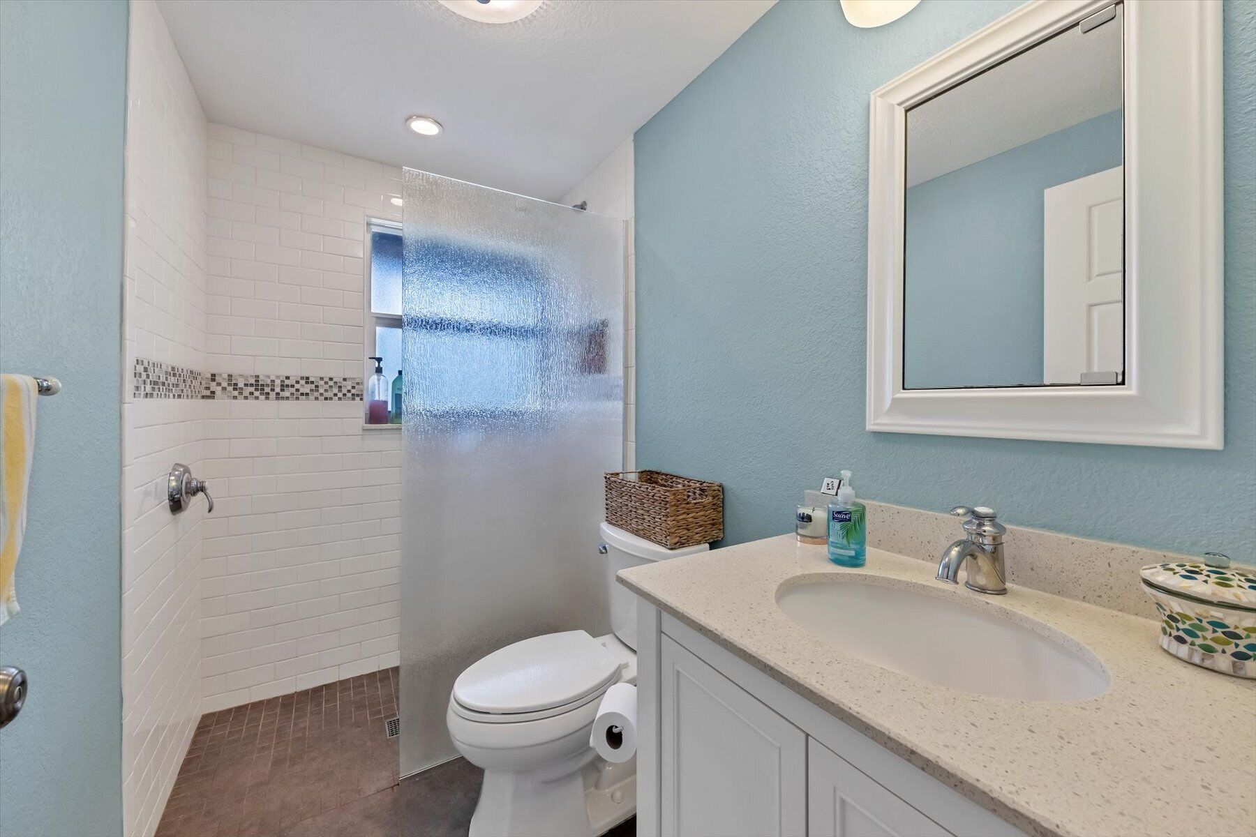 Un baño con ducha, inodoro, lavamanos y espejo.