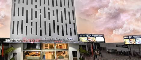 A modern hotel with a grid-like facade, a bar, and a parking area.