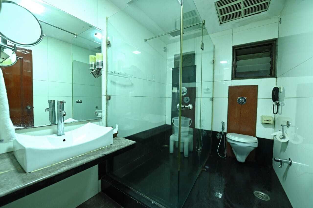 Un baño moderno con cabina de ducha de vidrio, un lavamanos blanco y un inodoro.