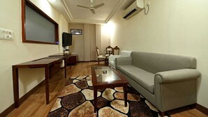 A living room with a sofa, coffee table, TV, and a patterned rug. - HOTEL SAGAR INTERNATIONAL (Durg)