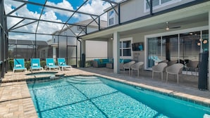 A swimming pool with lounge chairs and a covered patio area.