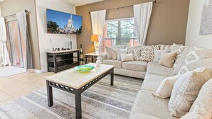 A living room with a sofa, a coffee table, a TV, and a painting of a castle. - SUG8970 Summary:<br>Para (Kissimmee)