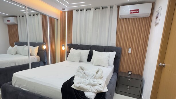 Une chambre moderne avec un grand lit, des tables de chevet, un miroir et un luminaire fixé au plafond.