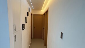 Un couloir moderne avec un plancher de couleur claire, des murs blancs et une porte en bois au fond.