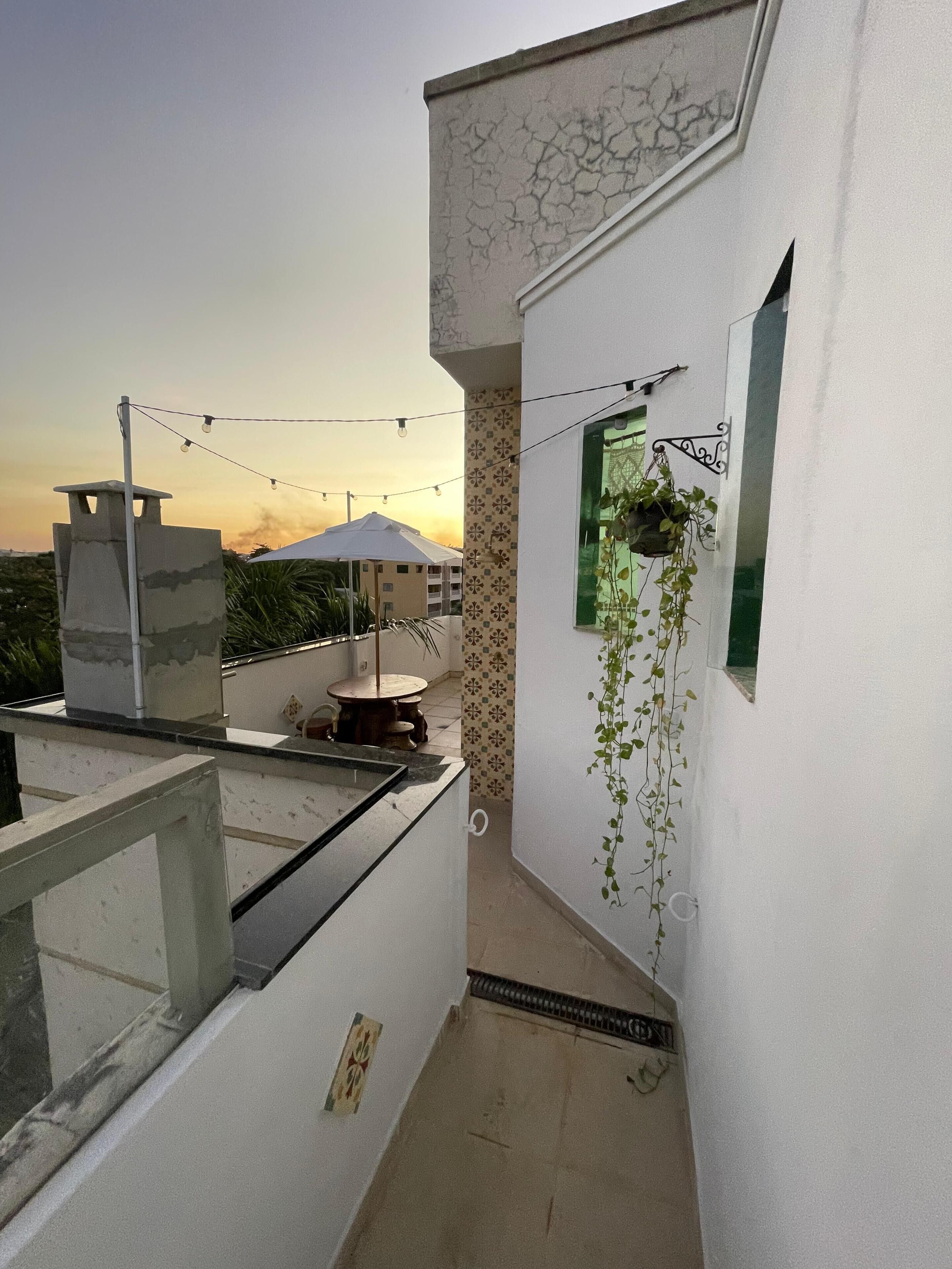 Ein schmaler Korridor mit einem kleinen Fenster, einer hängenden Pflanze und einer Lichterkette.