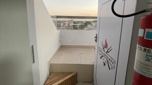 Een smalle gang die uitkomt op een balkon, met een brandblusser en een logo op de muur.