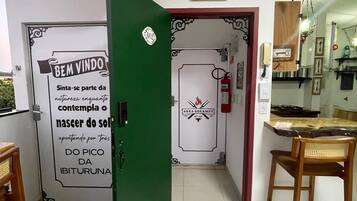 Una habitación con puerta verde, área de cocina y comedor con dos sillas de madera.