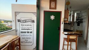Een balkon met een tafel en stoelen, een groene deur en een keuken die zichtbaar is door een open deur.