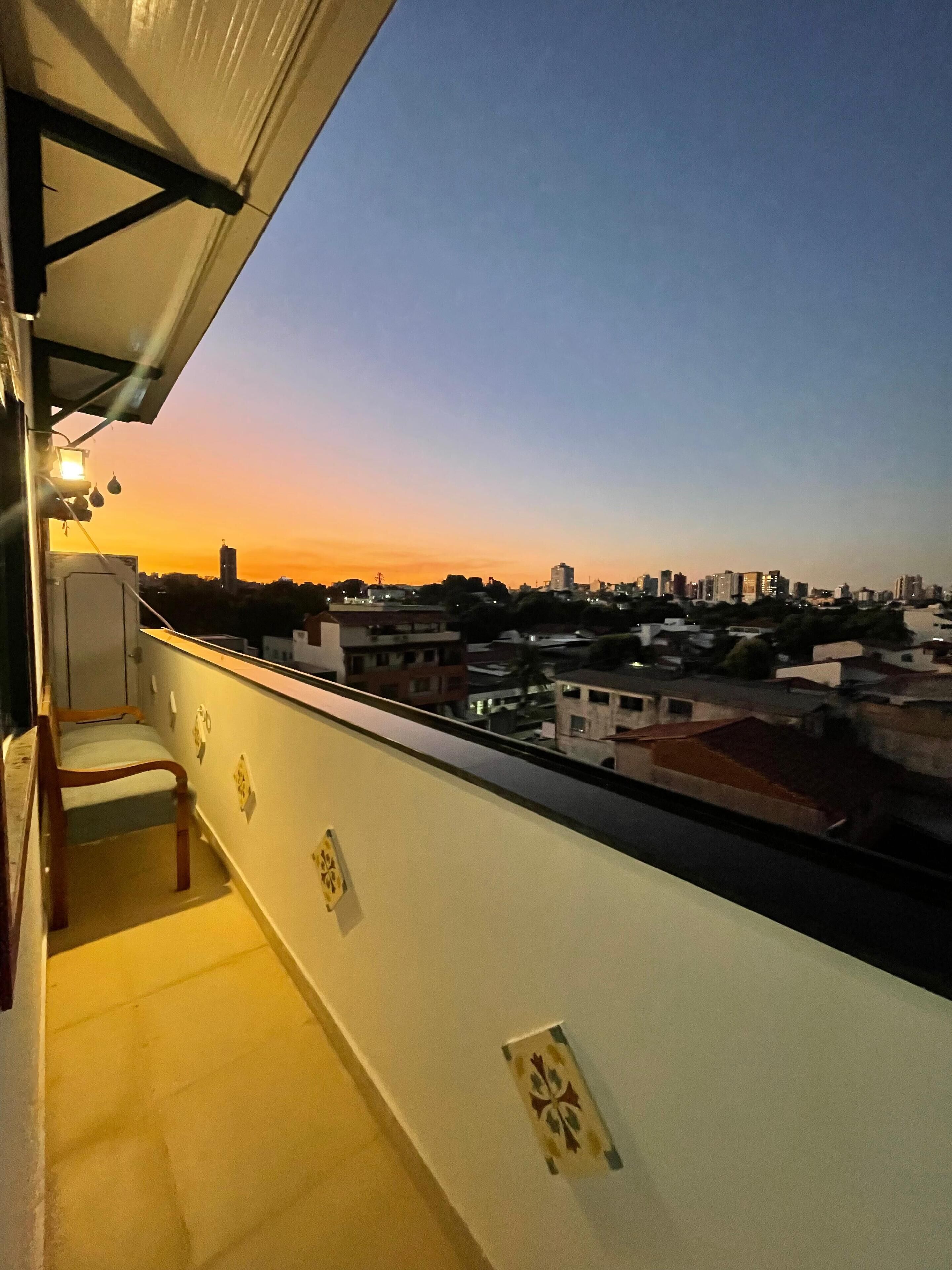 Ein Balkon mit Blick auf eine Stadtlandschaft bei Sonnenuntergang.