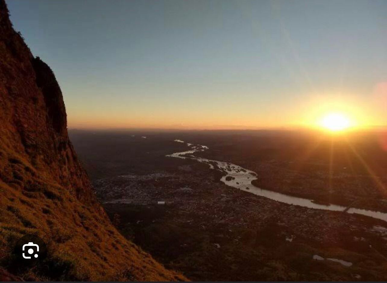 Ein Fluss fließt durch eine Stadt, im Hintergrund ein Sonnenuntergang.
