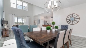 A spacious dining area with a wooden table, blue and white chairs, and a large wall clock. - KCC 4797 Summary:<br>Sto (Kissimmee)