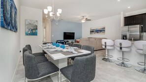 Uma sala de estar moderna com área de jantar, cozinha e bar.