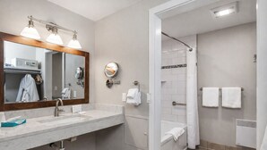 Un baño moderno con lavamanos de mármol, un espejo grande, ducha con puerta de cristal y toallas blancas.