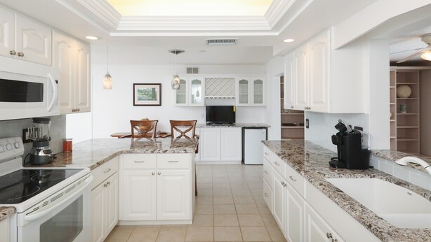 A modern kitchen with white cabinetry, a central island, a built-in oven, and a large sink. - Vgd27305 (Punta Gorda)
