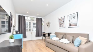 Un salon moderne avec un canapé, une table basse, un téléviseur et une fenêtre avec des rideaux.