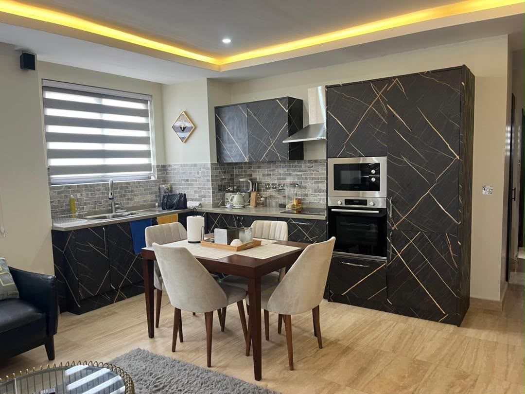A modern kitchen with a dining area, featuring a marble backsplash, built-in appliances, and a dining table with chairs.