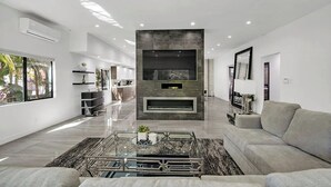A modern living room with a fireplace, a sofa, and a coffee table. - Mansfield Modern - Ultimate Entertainers Oasis With Guest House (Los Angeles)