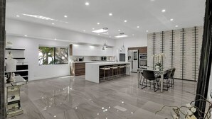 A modern kitchen with a central island, bar stools, pendant lighting, and a view of the outdoors. - Mansfield Modern - Ultimate Entertainers Oasis With Guest House (Los Angeles)