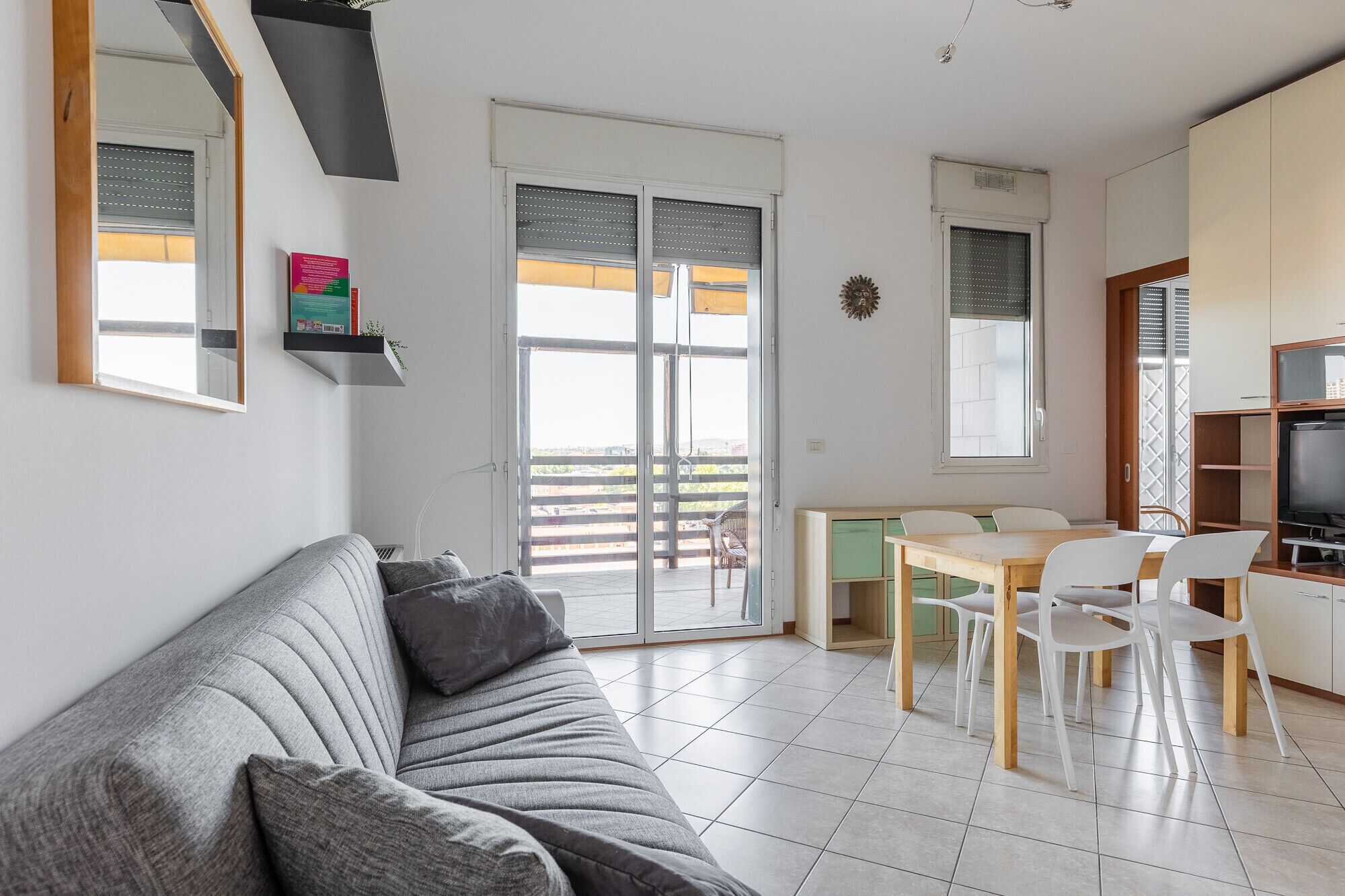 Een moderne woonkamer met een bank, een eettafel met stoelen en een televisie.