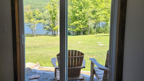 Una habitación con puerta corrediza de vidrio que da a un espacio exterior con una silla y un cartel que dice "Life's Better at the Lake".