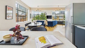 A modern kitchen with a large refrigerator, a dining area with a table and chairs, and a seating area with a sofa. - Spacious Two-Bedroom Haven by Tech City (Greater London)