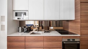 A modern kitchen with white cabinets, a built-in microwave, a coffee machine, and a dishwasher. - Luxury Apartment 4br/8p - Notre Dame / Bastille (Paris)