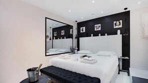 A modern hotel room with a large bed, a black bench, a bucket of champagne, and a mirror on the wall. - Intimate Flat w/ A/C & Jacuzzi - 2br/6p Montmartre (Paris)