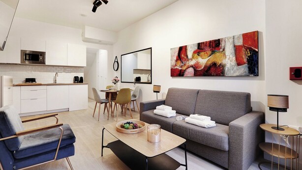 A modern living room with a grey sofa, a blue armchair, a wooden coffee table, and a dining area with a table and chairs. - Intimate Flat w/ A/C & Jacuzzi - 2br/6p Montmartre (Paris)