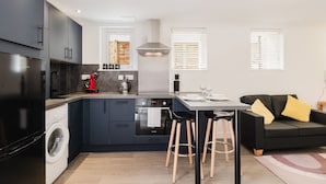 Una cocina compacta con lavadora, cafetera y zona de comedor con taburetes.