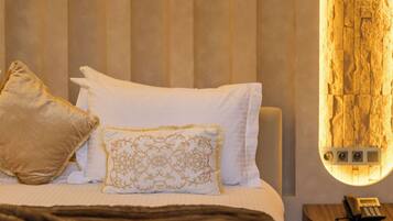 Una habitación de hotel con cama, almohadas, mesita de noche con teléfono y lámpara de pared.