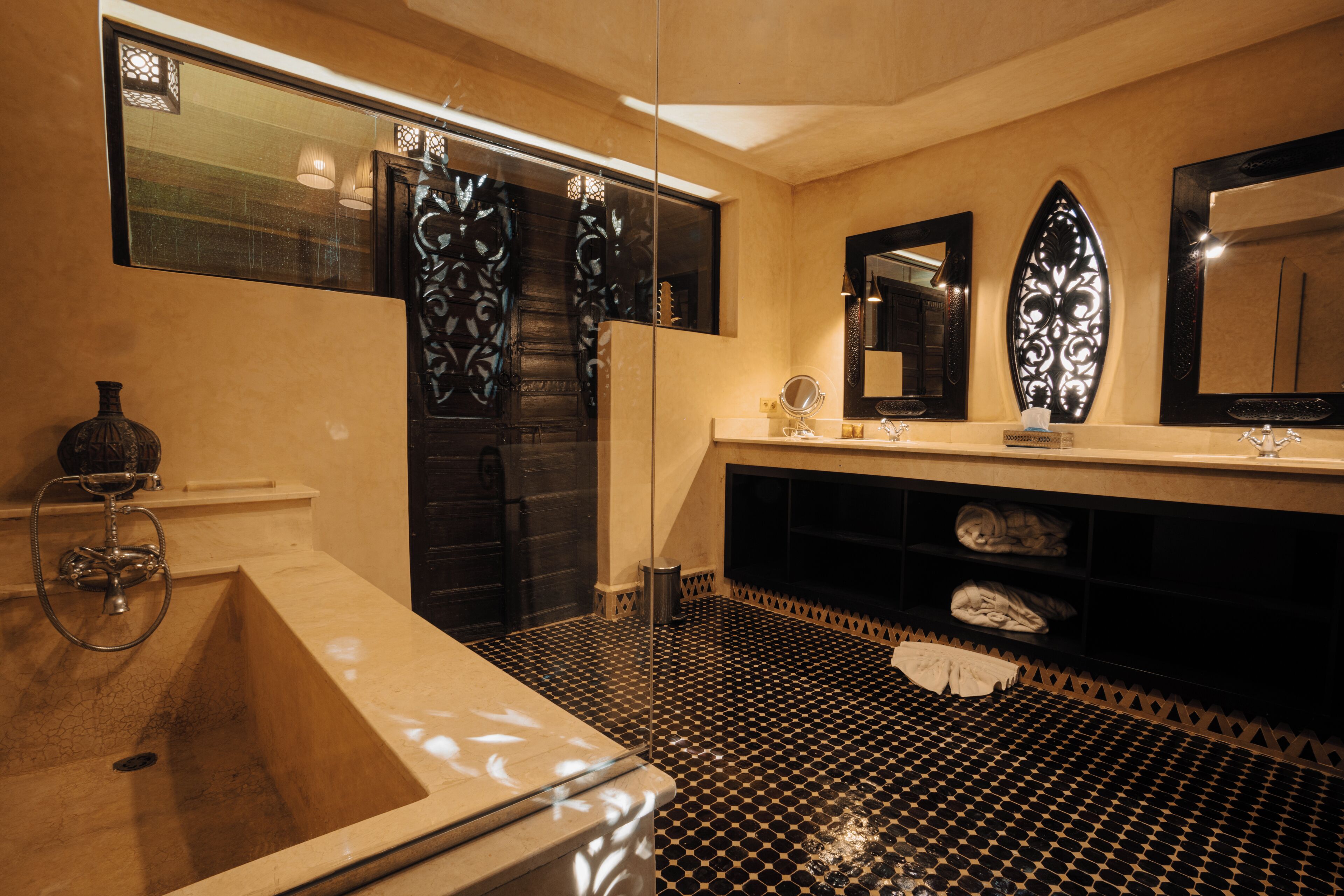 A bathroom with a large bathtub, a vanity with a mirror, and a decorative wall panel.