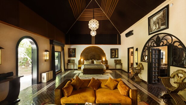 Una habitación amplia con un sofá grande, una mesa de centro y una cama con una cabecera original.