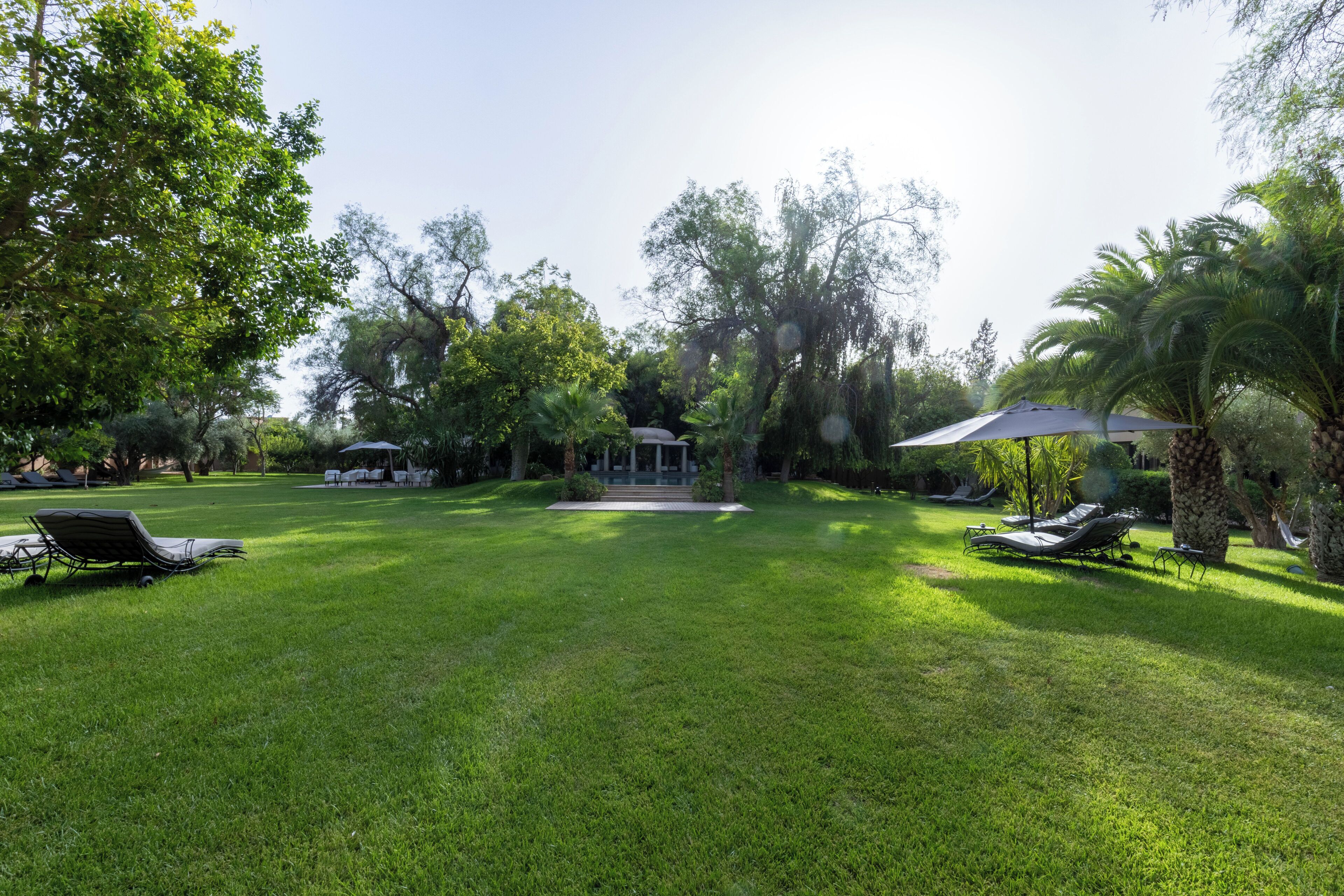 A well-maintained lawn with several lounge chairs and a gazebo.