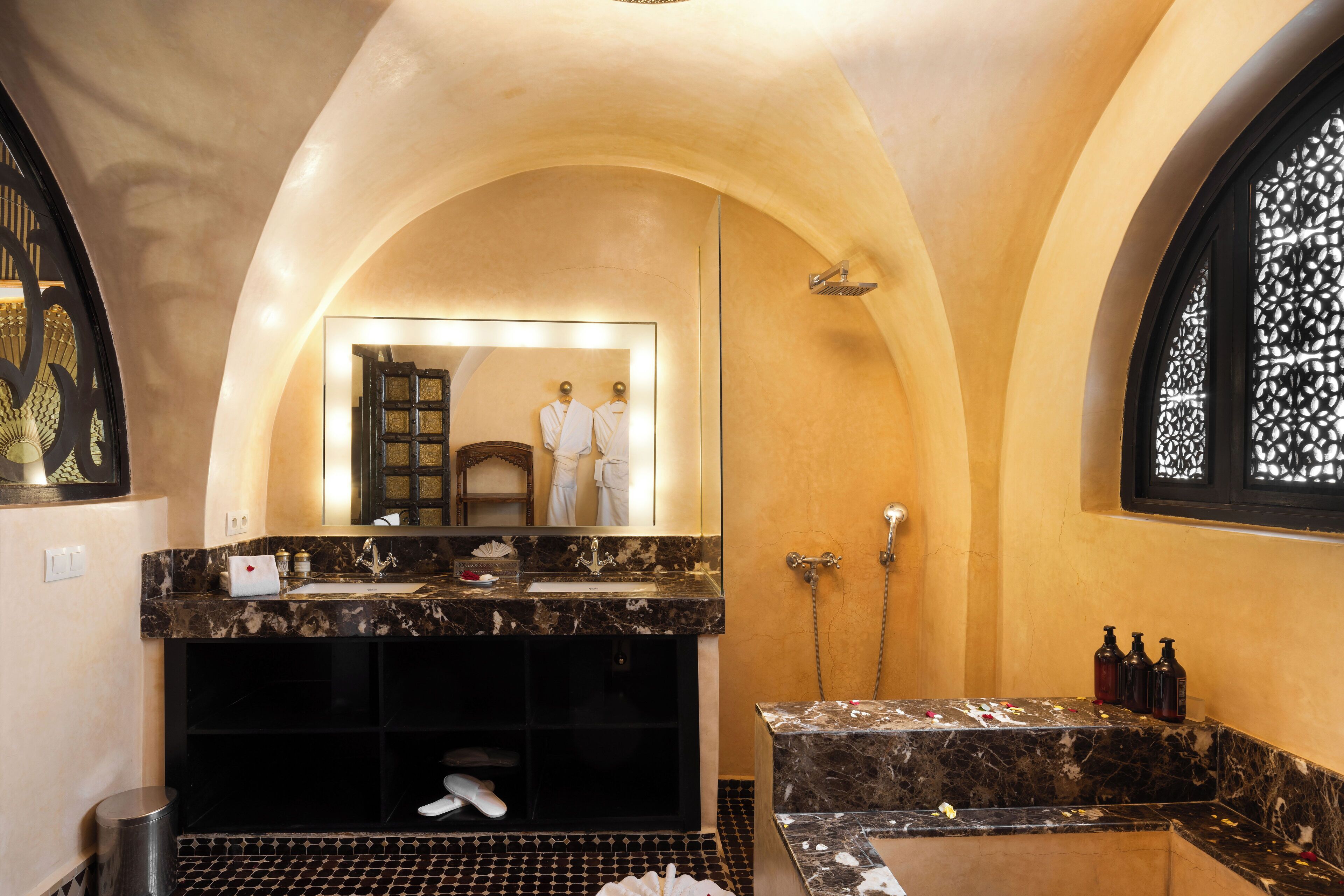 Ein Badezimmer mit Marmorwaschbecken, einem großen Spiegel und einer Dusche.