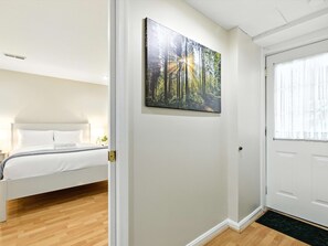 Un dormitorio con una cama, una puerta y un cuadro colgado en la pared que representa un paisaje forestal.