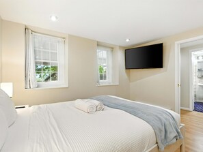 A bedroom with a bed, two windows, a TV, and a door leading to a bathroom. - Walk to METRO, Quiet 1BR, Near Rock Creek Park (Washington)