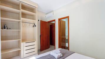 Un dormitorio con cama, un armario de madera y un baño visible a través de una puerta abierta.
