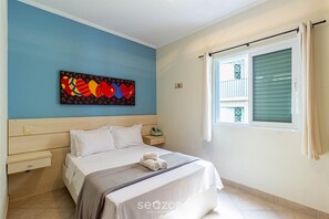 A bedroom with a bed, a nightstand, a wall art piece, a window with curtains, and a tiled floor. - Apart w Barbecue Grill 180m From the Beach Cgb0035 (Ubatuba)