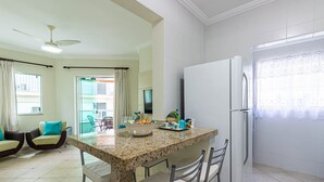 A modern kitchen with a granite countertop, a refrigerator, and a dining area with chairs and a table. - Apart w Barbecue Grill 180m From the Beach Cgb0035 (Ubatuba)