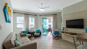 A living room with a sofa, chairs, a TV, and a balcony with curtains. - Apart w Barbecue Grill 180m From the Beach Cgb0035 (Ubatuba)