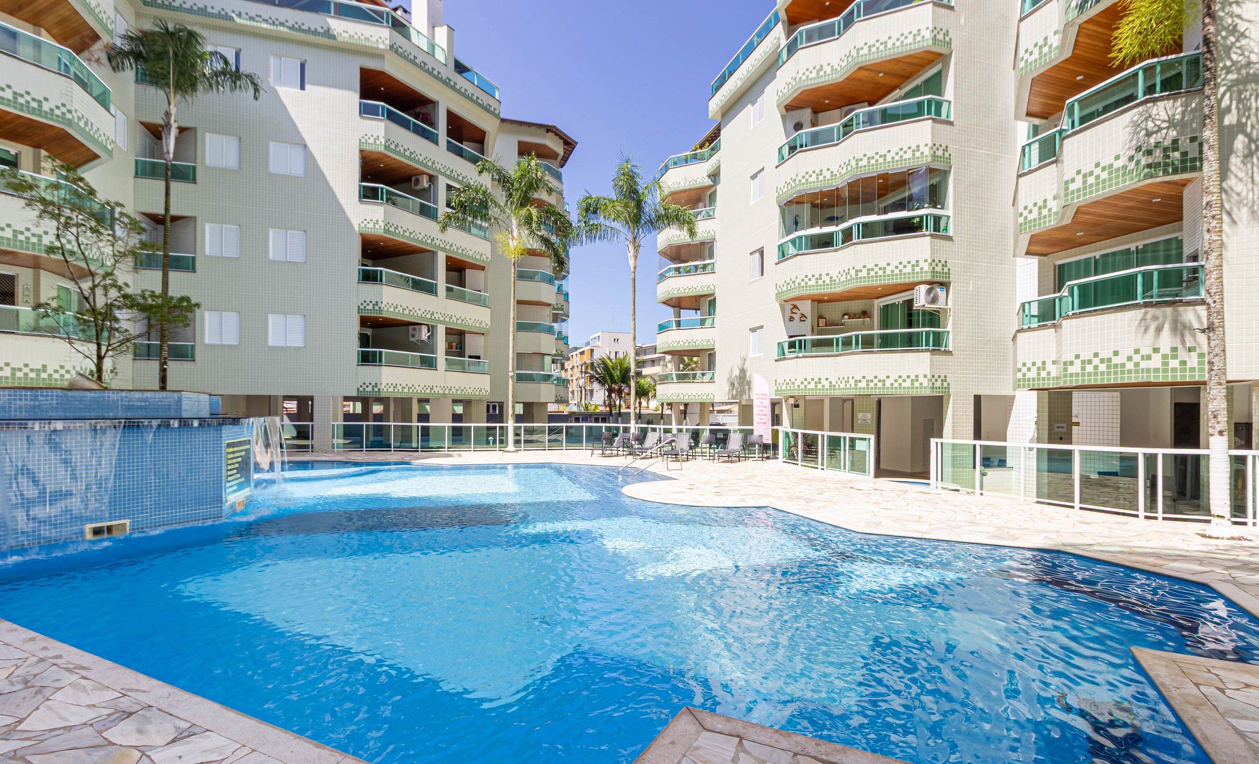A swimming pool surrounded by multi-story buildings with balconies and a tiled exterior.