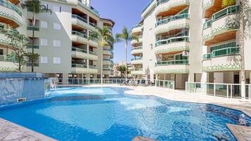 A swimming pool surrounded by multi-story buildings with balconies and a tiled exterior.