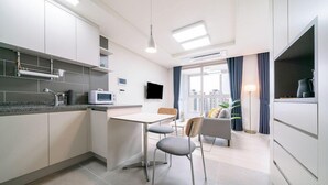 A modern kitchen with a dining area, a flat-screen TV, and a view of the city. - Urbanstay Incheon Songdo (Incheon)