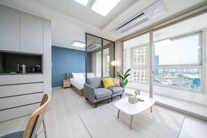 Una sala moderna con un sofá, una mesa de centro y un amplio ventanal con vista a la ciudad.