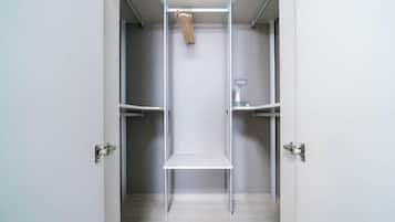 Un armario minimalista con barra para colgar y estante, con estructura metálica y un perchero de madera.