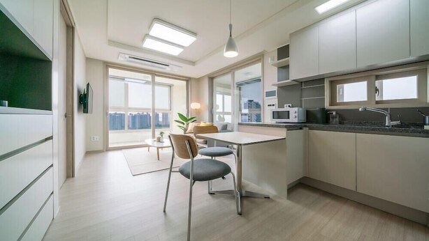 A modern kitchen with a dining area, large windows, and a view of the city. - Urbanstay Incheon Songdo (Incheon)
