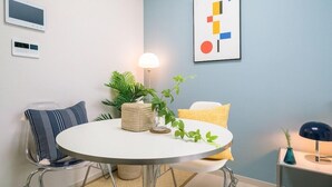 A modern room with a round table, clear chairs, a lamp, and a framed abstract artwork on the wall. - Urbanstay Incheon Songdo (Incheon)