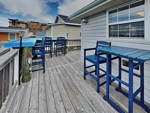 Eine Holzterrasse mit blauen Gartenmöbeln, darunter ein Tisch und Stühle, sowie ein Holzzaun.