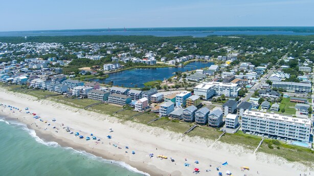 Eine Vogelperspektive einer Küstenstadt mit Strand, Wohnhäusern und einem großen Hotel.
