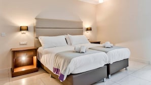 A double bed with a headboard, two bedside tables, and two wall-mounted lamps. - Villa Sardinella-5 Bedroom Villa With Private Pool (Mellieha)